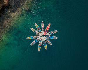 aerial view of a group of paddleboarders forming a star pattern on the clear blue waters