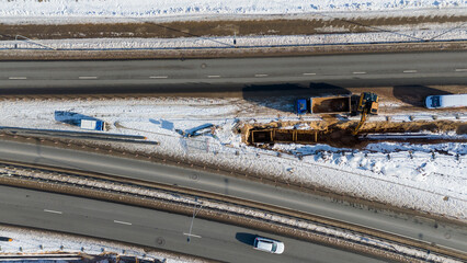 Drone photography of laying new sewage pipes near a road during winter day