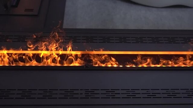 A bio-ethanol fireplace burns with orange flames in a dark room