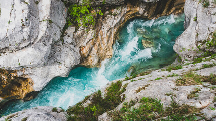 A breathtaking aerial view of the turquoise Soča or Isonzo river winding through rugged rock formations, capturing the raw beauty and power of nature.