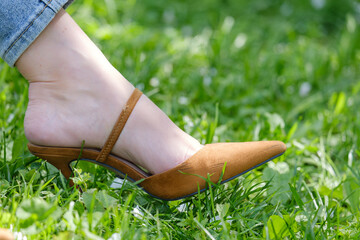 female feet in brown stiletto heels on the grass