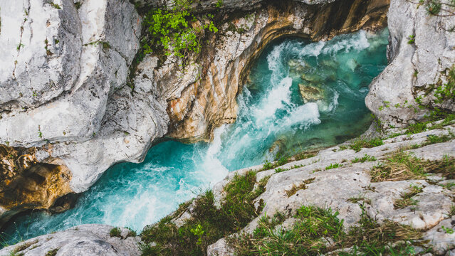 A breathtaking aerial view of the turquoise Soča or Isonzo river winding through rugged rock formations, capturing the raw beauty and power of nature.