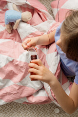 child on his bed pouring medicine into a spoon, top view