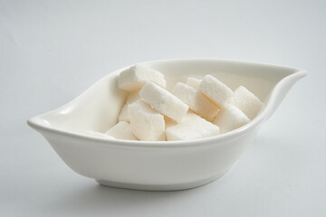 Sugar bowl with sugar cubes on white background