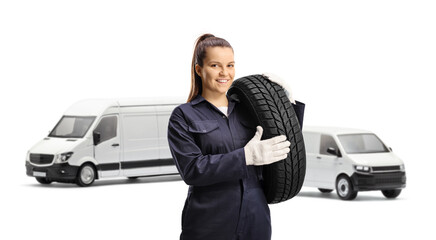 Young female mechanic worker carrying a van tire
