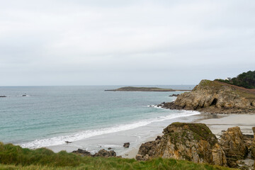 Une plage de sable bretonne, cernée de falaises majestueuses, offre une vue lointaine sur une...
