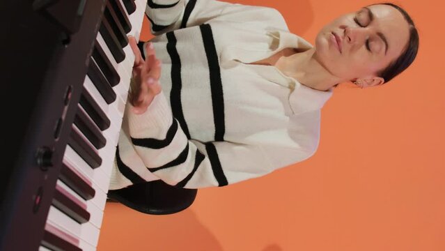 Young woman carefully performs composition on piano. Female pianist crafts melodies speaking to soul stirring imagination