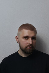 Fototapeta premium Portraits of a Millennial guy with a short haircut and beard, earrings in his ears