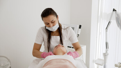 The cosmetologist applies chemical peeling. Close-up of beautician using cosmetic brush while...