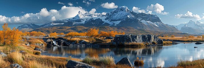 Amidst stunning scenery, a tranquil lake reflects snow-capped mountains, creating a colorful autumn scene.