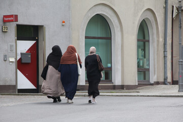 drei muslimische frauen spazieren über eine straße in neukölln