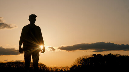 Silhouette of a man standing in front of a sunset