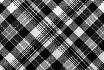 Texture of black and white fabric in a cage. Checkered material. Textile with intersecting white...