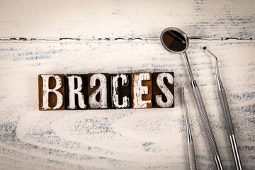 BRACES. Alphabet blocks and doctor tools on white wooden texture background - 794351663