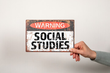 SOCIAL STUDIES. Warning sign with text in hand on light background - 794352037