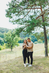 A happy family couple with a small newborn baby in their arms are standing in nature. Family vacation with a small child