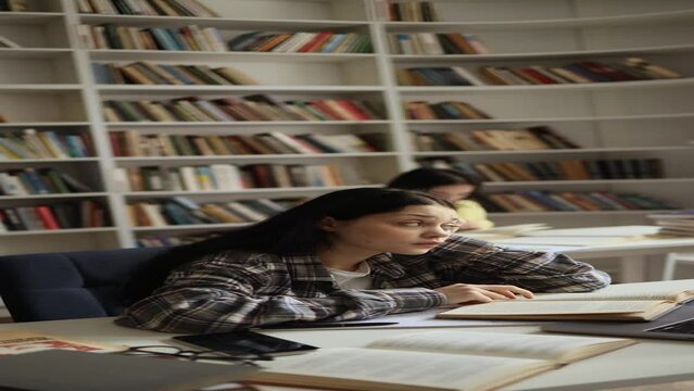 Vertical video of boring student girl feeling tired working at desk during study at university library Stressed young woman exhausted from remote distance work or education hard program indoors