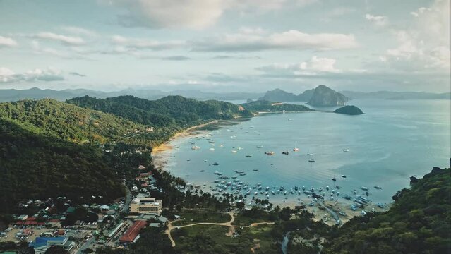 Pier town cityscape at ocean bay aerial view. Boats, yachts, ships at sea water. Tropical urban scape with houses, lodges, cottages at sand beach, green trees. Cinematic Philippines nature soft shot