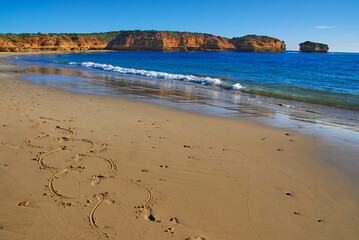 Drawing on a sandy beach by a human foot on a beautiful sunny day on the south coast of Victoria, Australia.