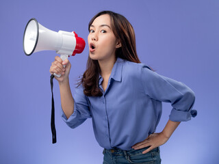 asian woman with megaphone, blue blouse, making an announcement on a vibrant purple background