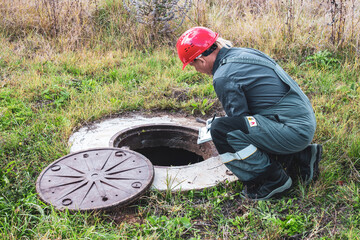Transfer of water meter readings. A municipal worker inspects a water meter in a water well, checking the readings