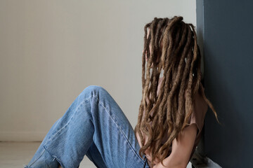 Side view portrait of unrecognizable woman with long dreadlocks sitting on floor minimal copy space