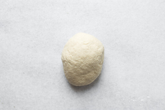 Coco bread dough rising on a a marble countertop, process of making jamaican coco bread