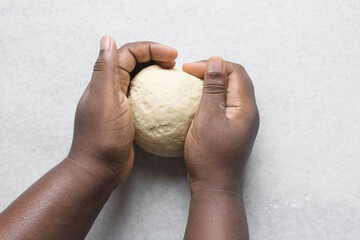 Overhead view of hands kneading dough on a marble countertop, bun dough being kneaded on a table,...