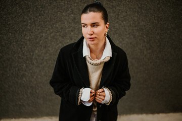 Classy young woman with piercings wearing coat and looking away on street.