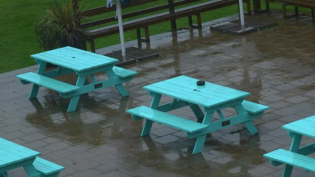 Static clip of mpty outdoor seating area at a cafe hotel drenched in rain