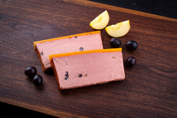 Traditional French veal liver pate with red grapes and apples offered as close-up on a wooden design board with text field