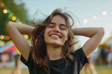Portrait of a beautiful young woman smiling with her eyes closed and her hands behind her head.