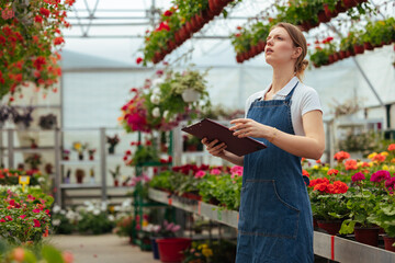 Fototapeta na wymiar Woman with a clipboard standing in greenhouse