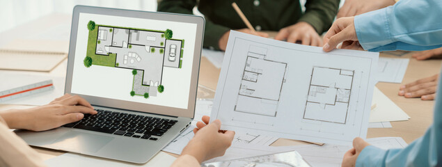 Fototapeta premium Professional architect decide the blueprint for eco-friendly house during discussion about changing blueprint plan at meeting table with architectural document scatter around. Closeup. Delineation