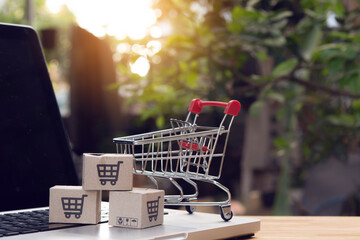 Shopping online. cardboard box with a shopping cart logo and empty trolley on laptop keyboard....