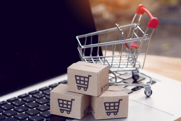 Shopping online. cardboard box with a shopping cart logo and empty trolley on laptop keyboard....