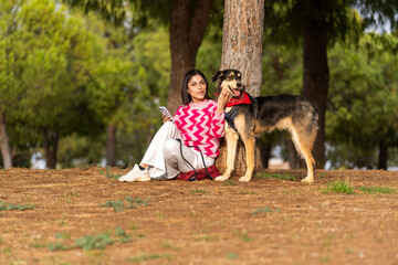 A beautiful woman enjoys a peaceful moment in a lush park with her faithful dog by her side,...