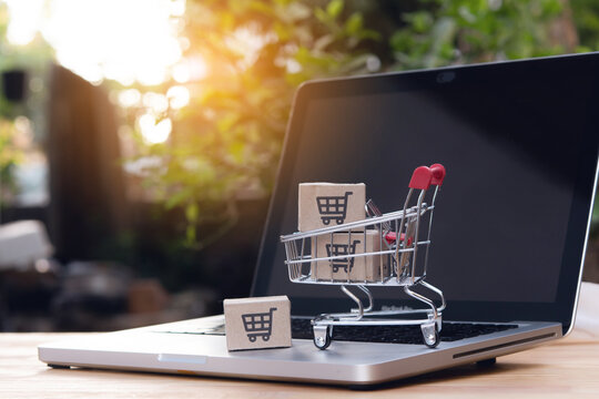 Shopping online. cardboard box with a shopping cart logo in a trolley on laptop keyboard. Shopping service on The online web. offers home delivery - Powered by Adobe