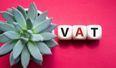 VAT - Value Added Tax symbol. Wooden cubes with word VAT. Beautiful red background with succulent...