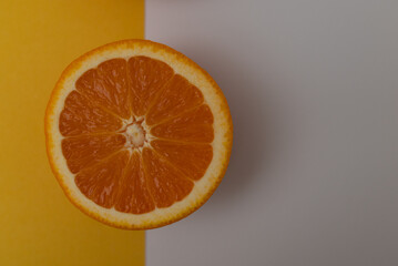 one oranges are cut in half and placed on a yellow and white background. The oranges are the main focus of the image, and the background is meant to complement the oranges