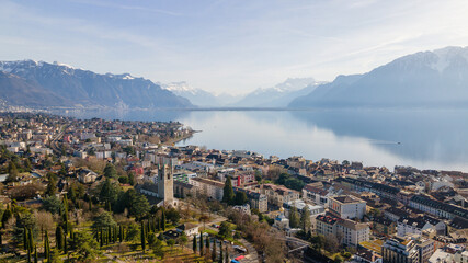 Fototapeta na wymiar Aerial view of dense buildings near the water with mountains under the clouds in Vevey, Switzerland