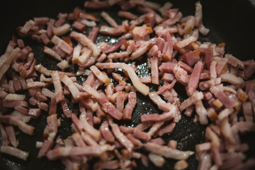 Bacon cut in dices being fried and cooked on a pan