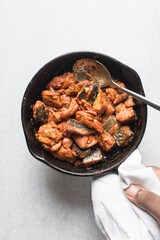 Overhead view of Sauteed spicy mackerel in a cast iron skillet, top view of chili fish chunks