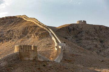 Ancient fortress walls on rugged mountain at sunset, Ranikot, Sindh, Pakistan