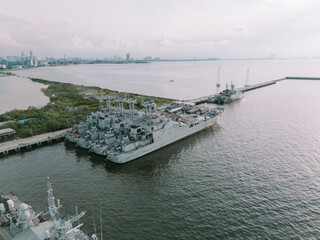Photo of a naval warship docked at the pier, showcasing military power and readiness, against the backdrop of the harbor.