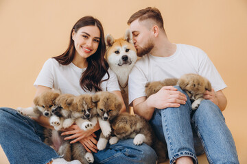Happy beautiful couple in love caring and playing with little funny puppies and their mother dog on...