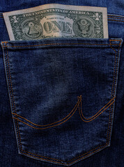 Banknote of north american one dollar bill in blue jeans pocket background. bill of 1 american bucks sticking out of back denim pocket. US Currency. american eagle with arrows, olive branch, pyramid