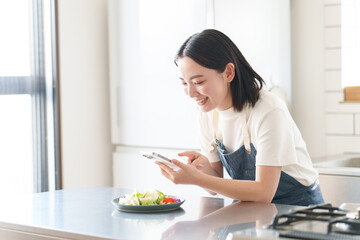 スマートフォンで料理の写真を撮る女性