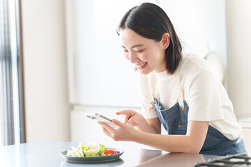 Obraz na płótnie Canvas スマートフォンで料理の写真を撮る女性