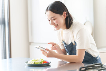 スマートフォンで料理の写真を撮る女性